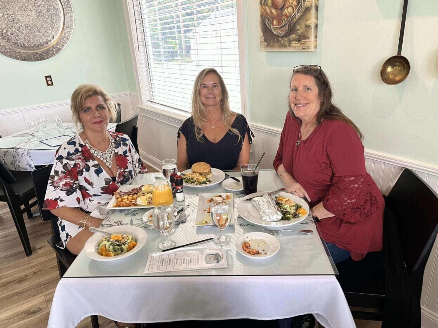 Three women enjoying a meal together at a bright dining table.