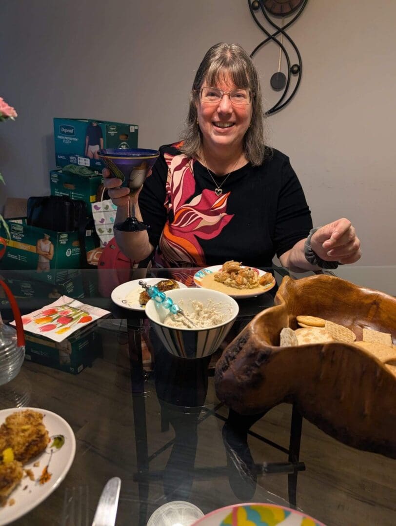 Smiling woman enjoying a meal at a cozy dining table with various dishes.