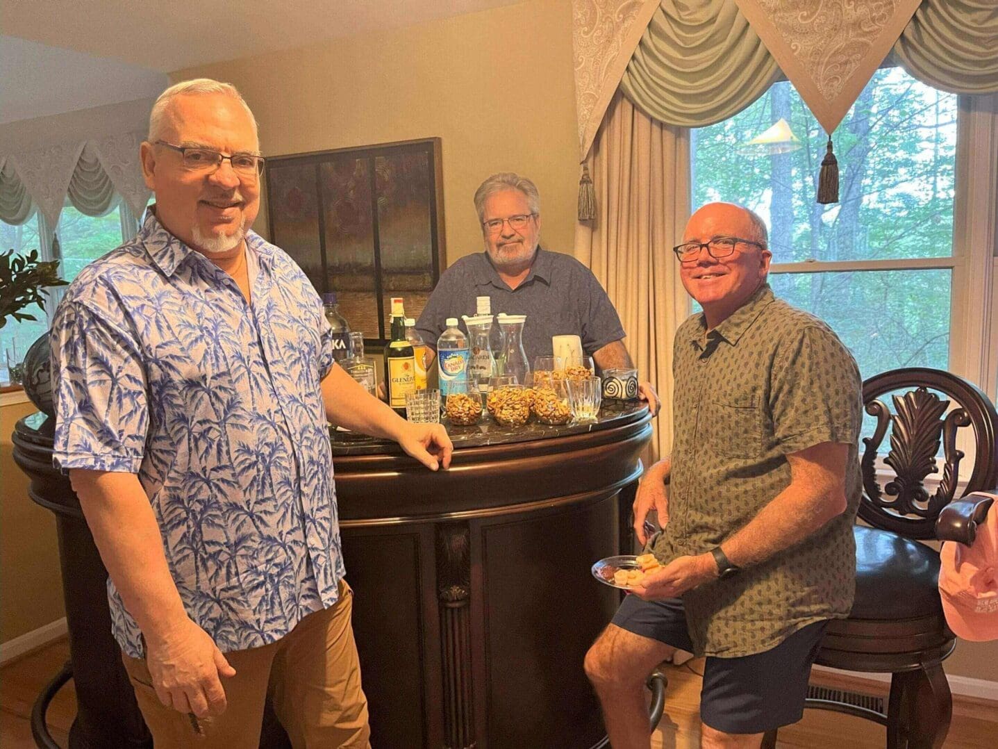 Three men enjoying drinks and conversation indoors near a window.