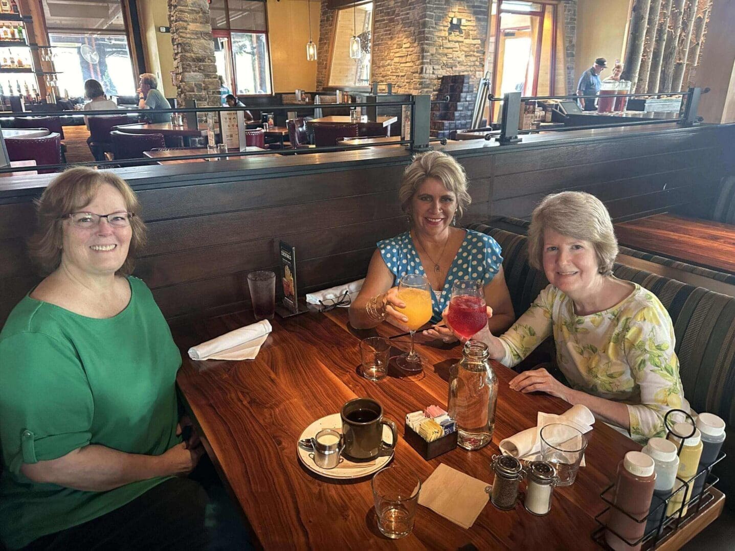 Three women enjoying drinks and desserts at a cozy café.