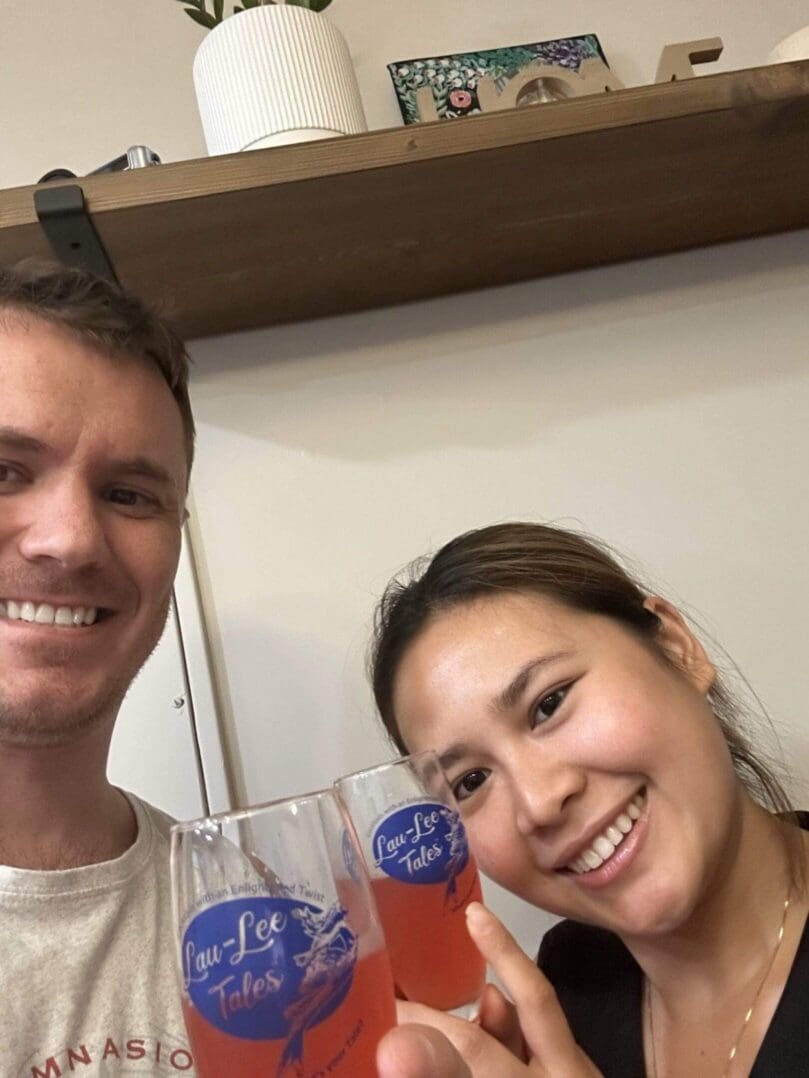 A smiling man and woman holding glasses with drinks indoors.