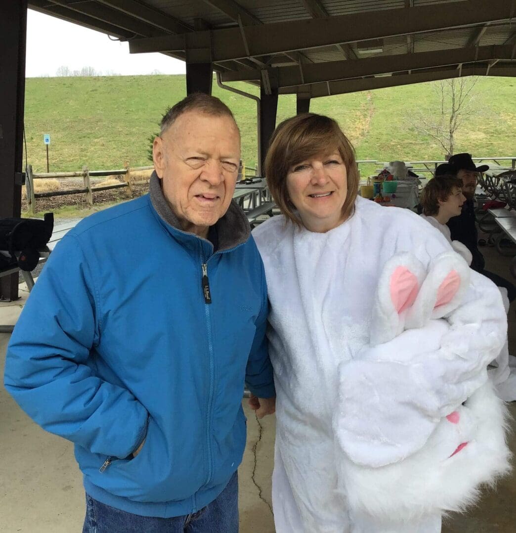 Man with woman in bunny costume outdoors.